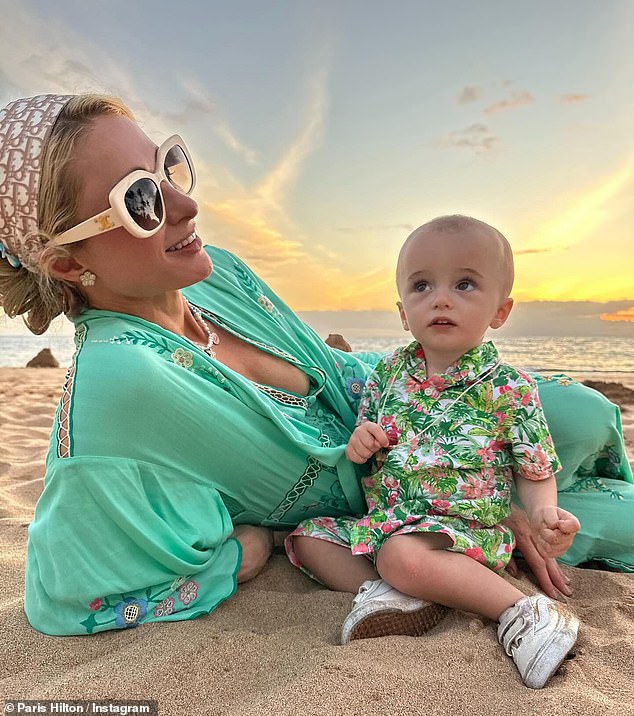 With London and Phoenix in her lap, Hilton relaxed in the sand while wearing a flowing light green floral-print dress